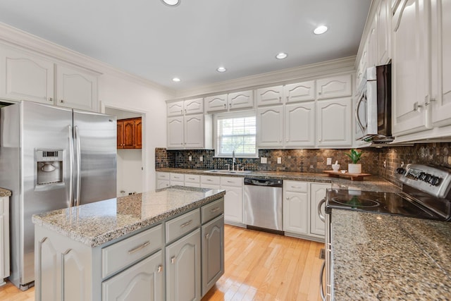 kitchen featuring appliances with stainless steel finishes, a sink, crown molding, tasteful backsplash, and a kitchen island