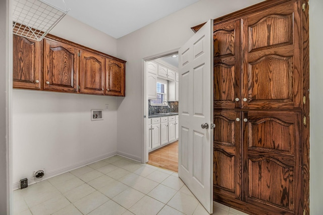 clothes washing area featuring cabinet space, washer hookup, light tile patterned floors, and baseboards