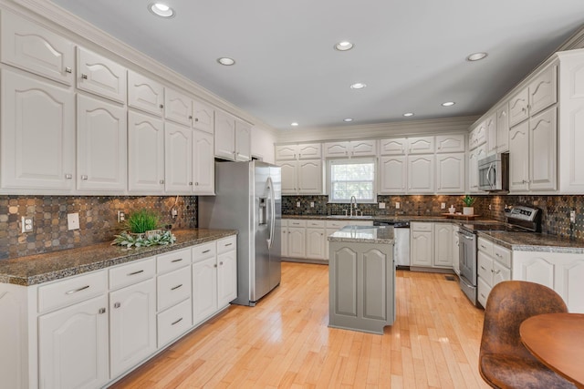 kitchen featuring stainless steel appliances, crown molding, tasteful backsplash, light wood-style flooring, and a sink