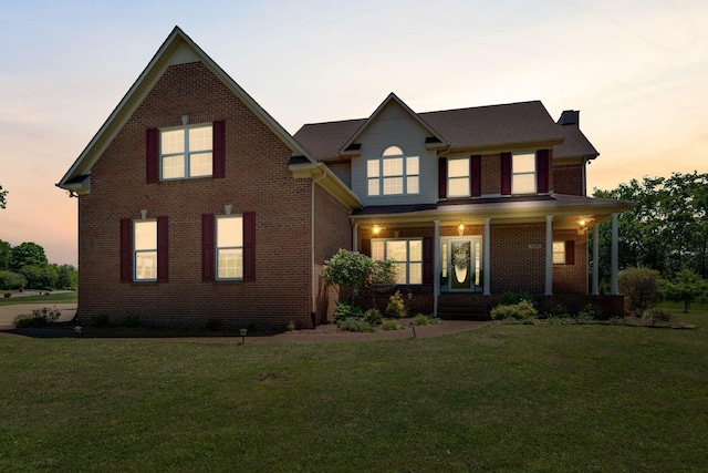 traditional-style house featuring a porch, a chimney, and a front yard