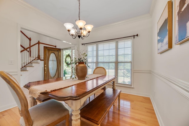 dining space featuring stairs, a chandelier, plenty of natural light, light wood-style flooring, and crown molding