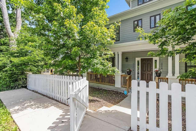 entrance to property featuring covered porch and fence