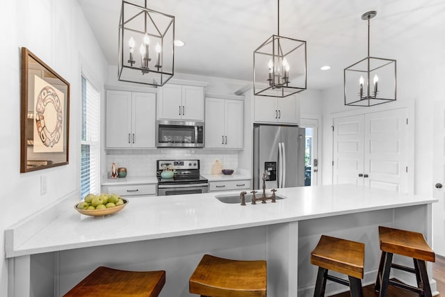 kitchen featuring stainless steel appliances, a chandelier, a sink, tasteful backsplash, and recessed lighting
