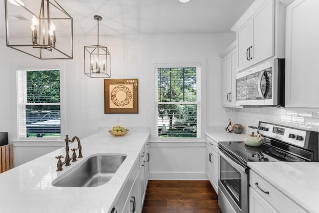 kitchen with stainless steel appliances, a sink, a chandelier, dark wood finished floors, and backsplash