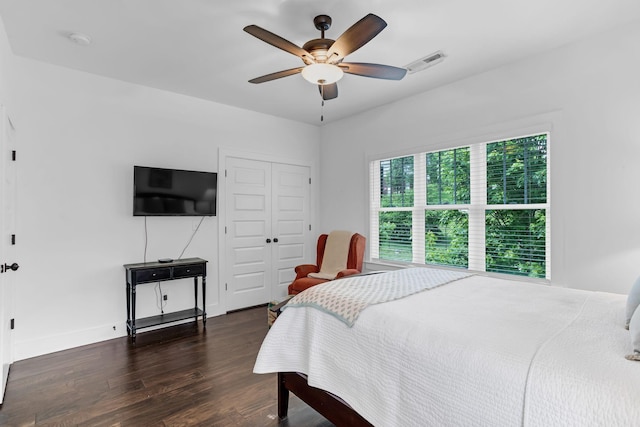 bedroom featuring dark wood-style flooring, a closet, a ceiling fan, and baseboards