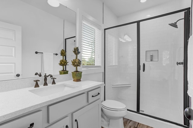 full bathroom featuring a stall shower, vanity, toilet, and wood finished floors