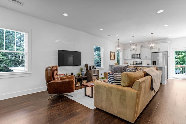 living room featuring dark wood-type flooring, recessed lighting, a chandelier, and baseboards