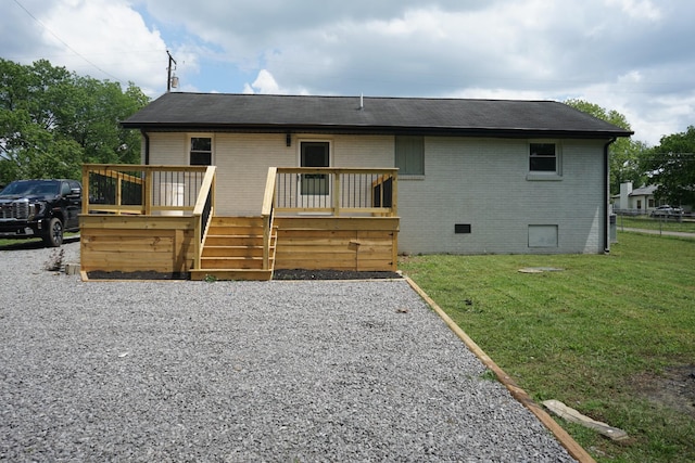 back of house with brick siding, a lawn, a deck, and a shingled roof