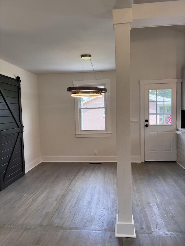 foyer entrance featuring wood finished floors, baseboards, and a barn door