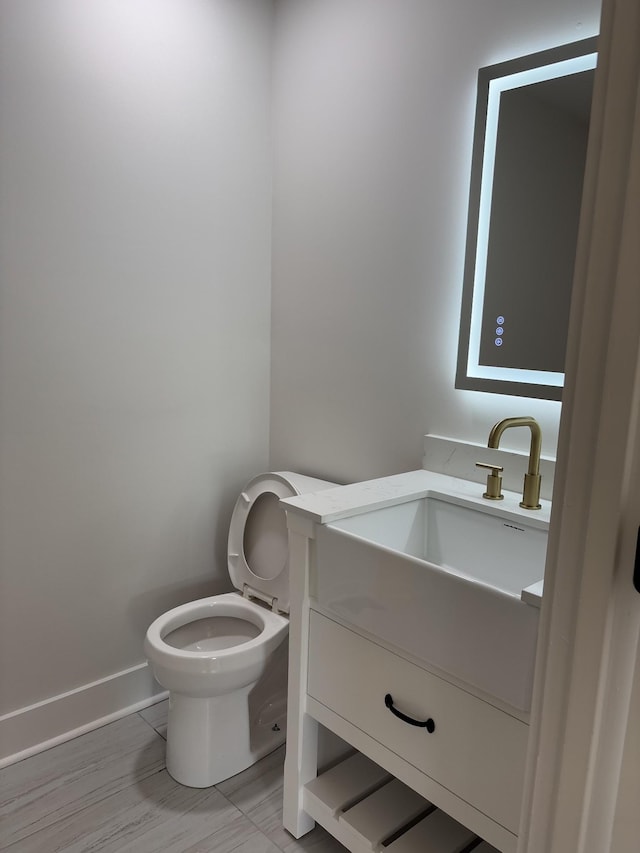 bathroom with vanity, baseboards, and toilet