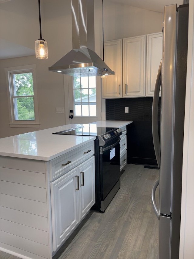 kitchen with freestanding refrigerator, black electric range, wall chimney exhaust hood, light wood-type flooring, and white cabinetry