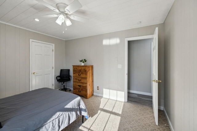 bedroom featuring carpet, baseboards, ceiling fan, crown molding, and wooden walls