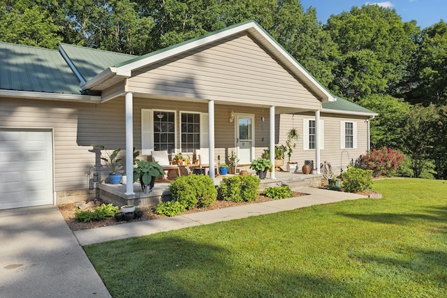 back of property with a porch, a yard, metal roof, an attached garage, and concrete driveway