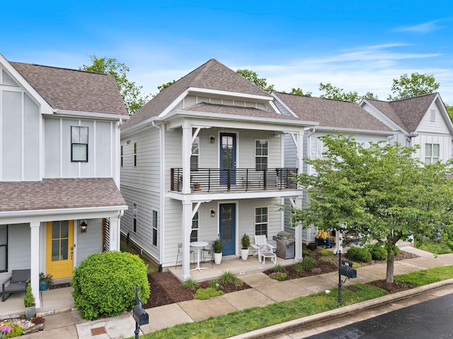 view of front of property featuring a balcony, roof with shingles, and a patio area