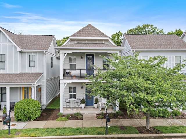 view of front of house featuring a balcony, roof with shingles, and covered porch