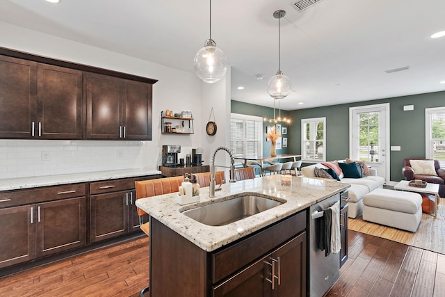 kitchen featuring stainless steel dishwasher, a sink, open floor plan, dark brown cabinets, and recessed lighting