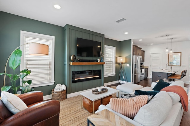 living room featuring baseboards, recessed lighting, dark wood-type flooring, and a fireplace