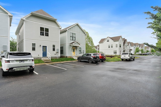 view of front of home with board and batten siding, uncovered parking, entry steps, and a residential view