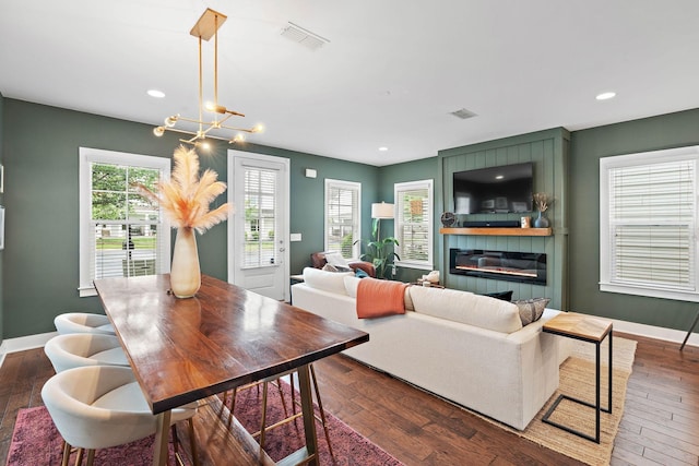 dining room featuring dark wood-style flooring, a fireplace, baseboards, recessed lighting, and a chandelier