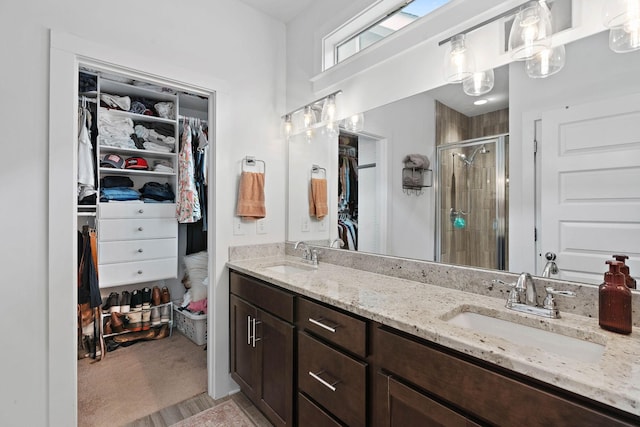 full bath featuring a shower stall, a spacious closet, and double vanity