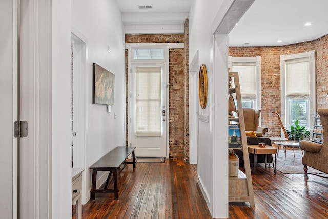 entrance foyer featuring brick wall and dark wood-style floors