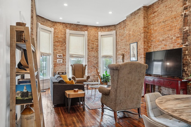 living area featuring hardwood / wood-style flooring, brick wall, and recessed lighting