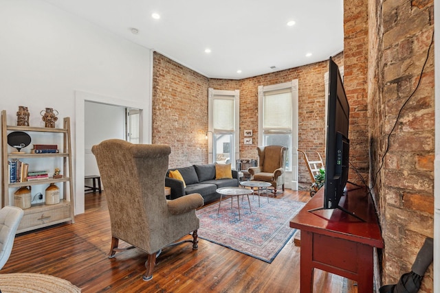 living area with brick wall, hardwood / wood-style floors, and recessed lighting