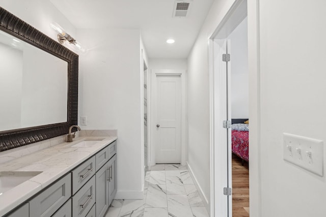 ensuite bathroom featuring baseboards, marble look tile flooring, recessed lighting, and double vanity
