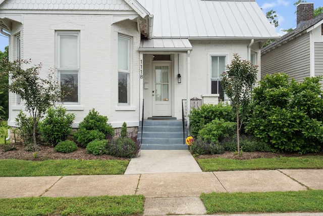 view of front of property featuring a standing seam roof, brick siding, and metal roof