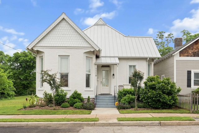 view of front of house featuring fence, brick siding, and a standing seam roof
