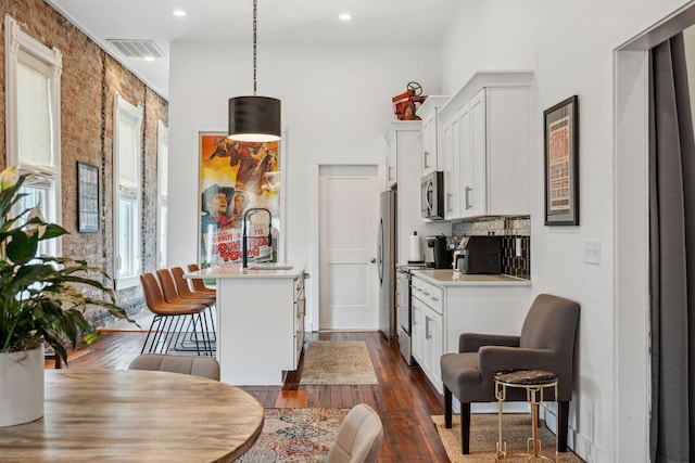 kitchen with a sink, stainless steel appliances, a kitchen bar, plenty of natural light, and recessed lighting