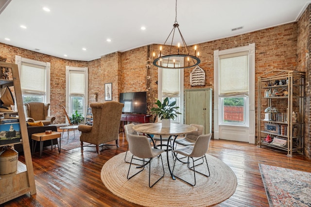 dining area featuring brick wall, healthy amount of natural light, a chandelier, hardwood / wood-style floors, and recessed lighting