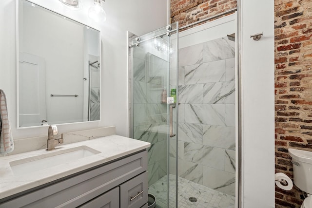 bathroom with brick wall, toilet, a shower stall, and vanity