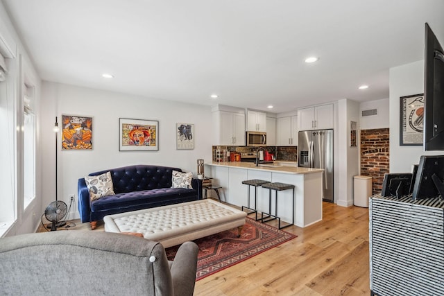 living area with light wood finished floors and recessed lighting