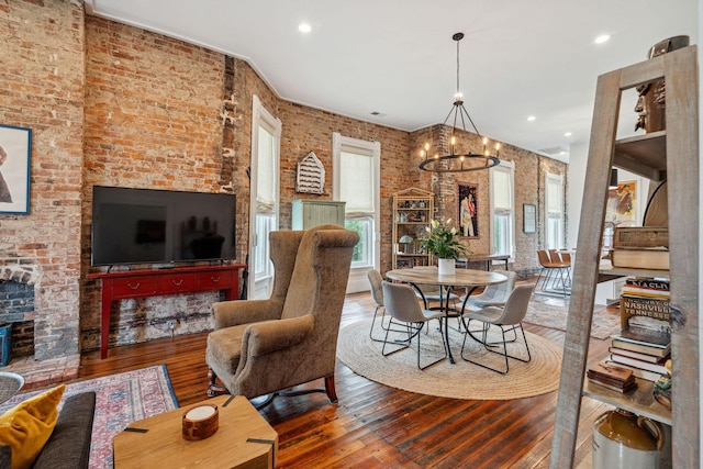 living room with hardwood / wood-style floors, a chandelier, brick wall, and recessed lighting