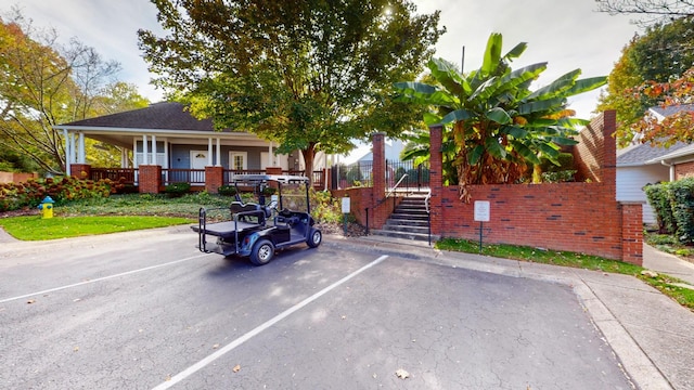 view of front of house featuring covered porch, brick siding, stairs, and uncovered parking