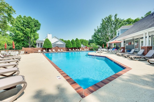 community pool with a patio area and fence