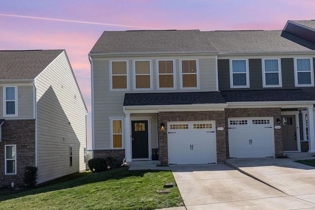 view of front of home featuring an attached garage, concrete driveway, a lawn, stone siding, and roof with shingles