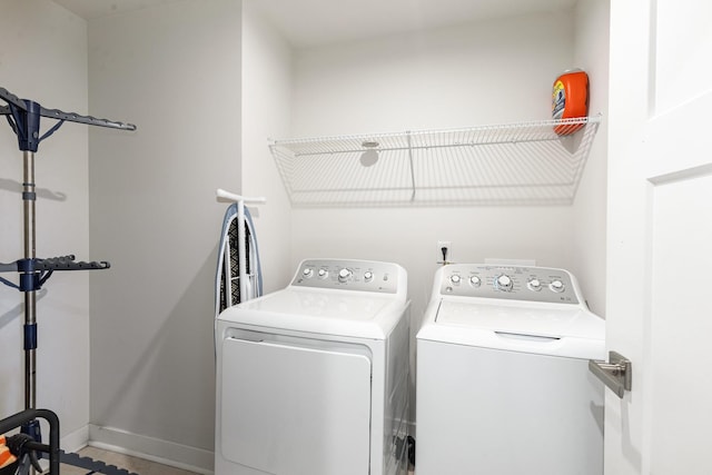 clothes washing area featuring separate washer and dryer and baseboards