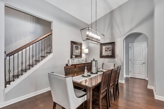 dining space featuring baseboards, dark wood-style flooring, a high ceiling, arched walkways, and stairway