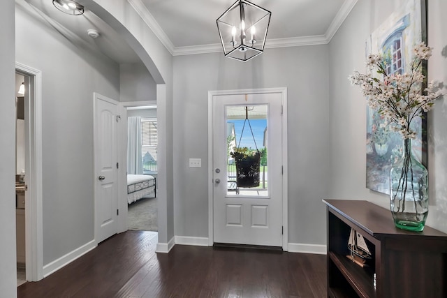 foyer entrance with arched walkways, crown molding, dark wood finished floors, baseboards, and a chandelier