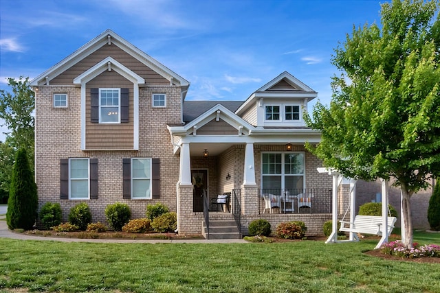 view of front of property featuring a porch, a front yard, and brick siding
