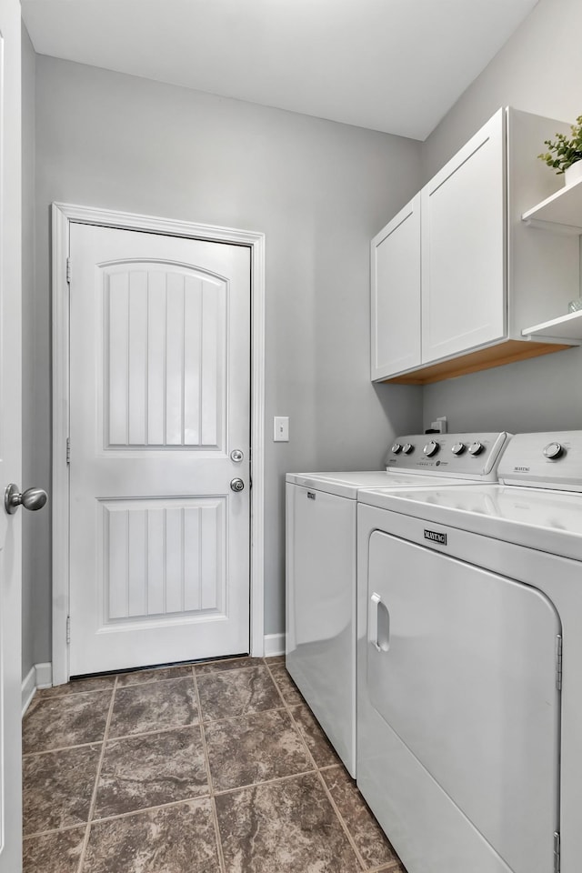 clothes washing area with cabinet space, independent washer and dryer, and baseboards