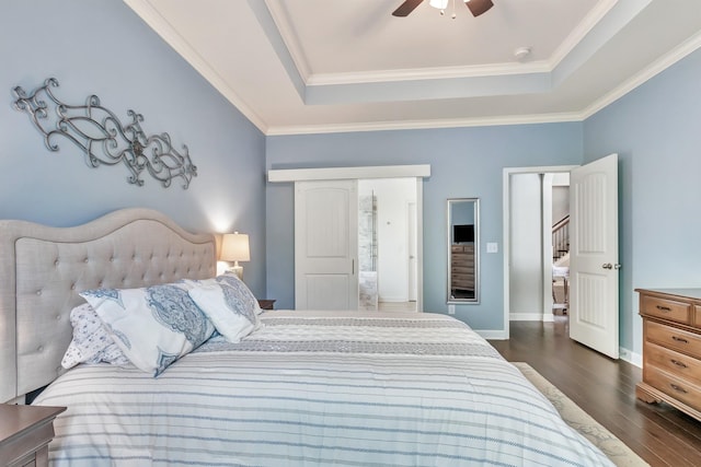 bedroom with a tray ceiling, dark wood finished floors, crown molding, a ceiling fan, and baseboards