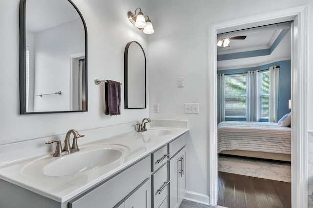 full bath featuring ensuite bath, wood finished floors, double vanity, ornamental molding, and baseboards