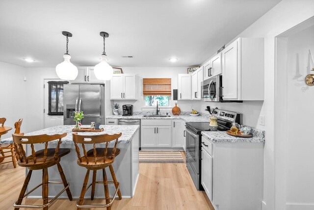 5921 Keysburg Rd, Adams, TN 37010 - kitchen featuring stainless steel appliances, light wood finished floors, a sink, a kitchen bar, and a kitchen island