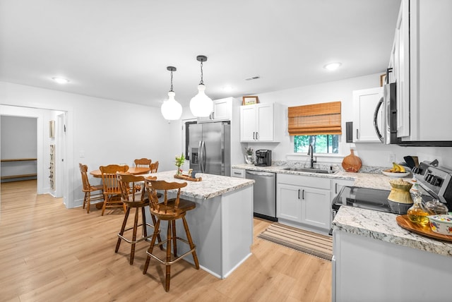 5921 Keysburg Rd, Adams, TN 37010 - kitchen featuring appliances with stainless steel finishes, a sink, light wood-type flooring, a kitchen bar, and light stone counters