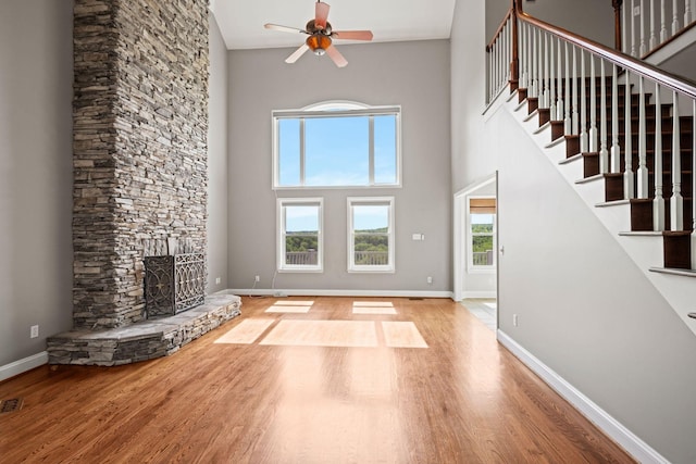 1709 Wildlife Trl, Kingston Springs, TN 37082 - unfurnished living room with ceiling fan, wood finished floors, a towering ceiling, a fireplace, and stairway