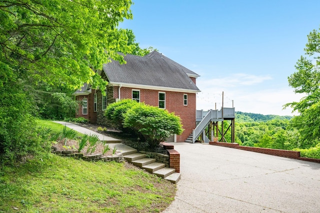 1709 Wildlife Trl, Kingston Springs, TN 37082 - view of side of property with stairs, concrete driveway, brick siding, and roof with shingles