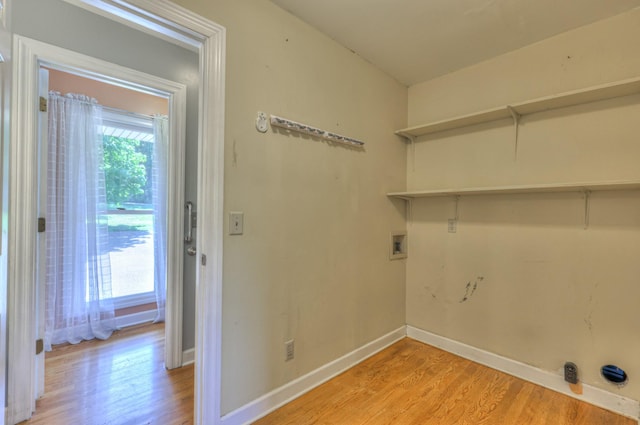 clothes washing area with light wood-style floors, hookup for a washing machine, and baseboards